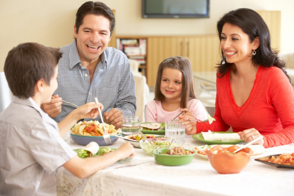 Young Hispanic Family Enjoying Meal At Home